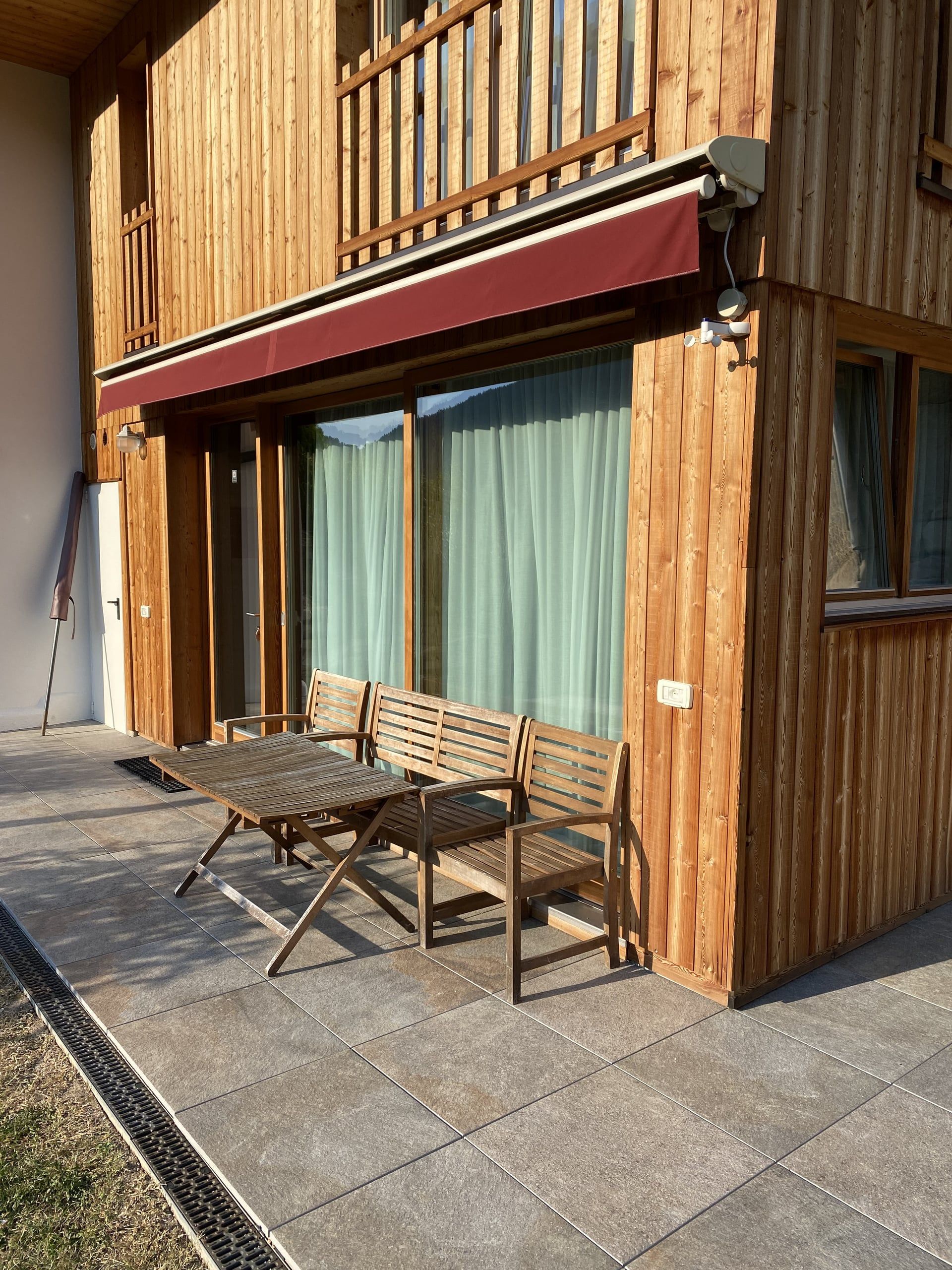 Terrasse des Apartments Buche mit Holztisch und Stühlen vor der Holzfassade