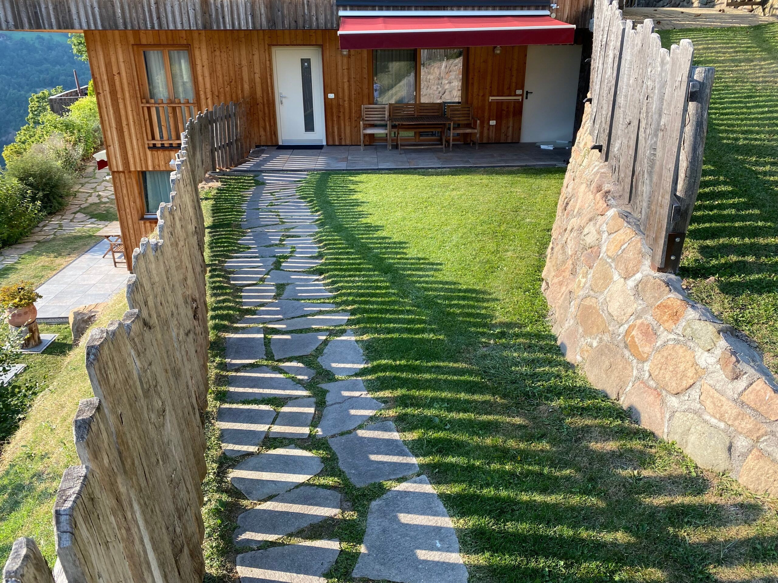 Eingangsbereich des Apartments Lärche mit Steinplattenweg und Rasen