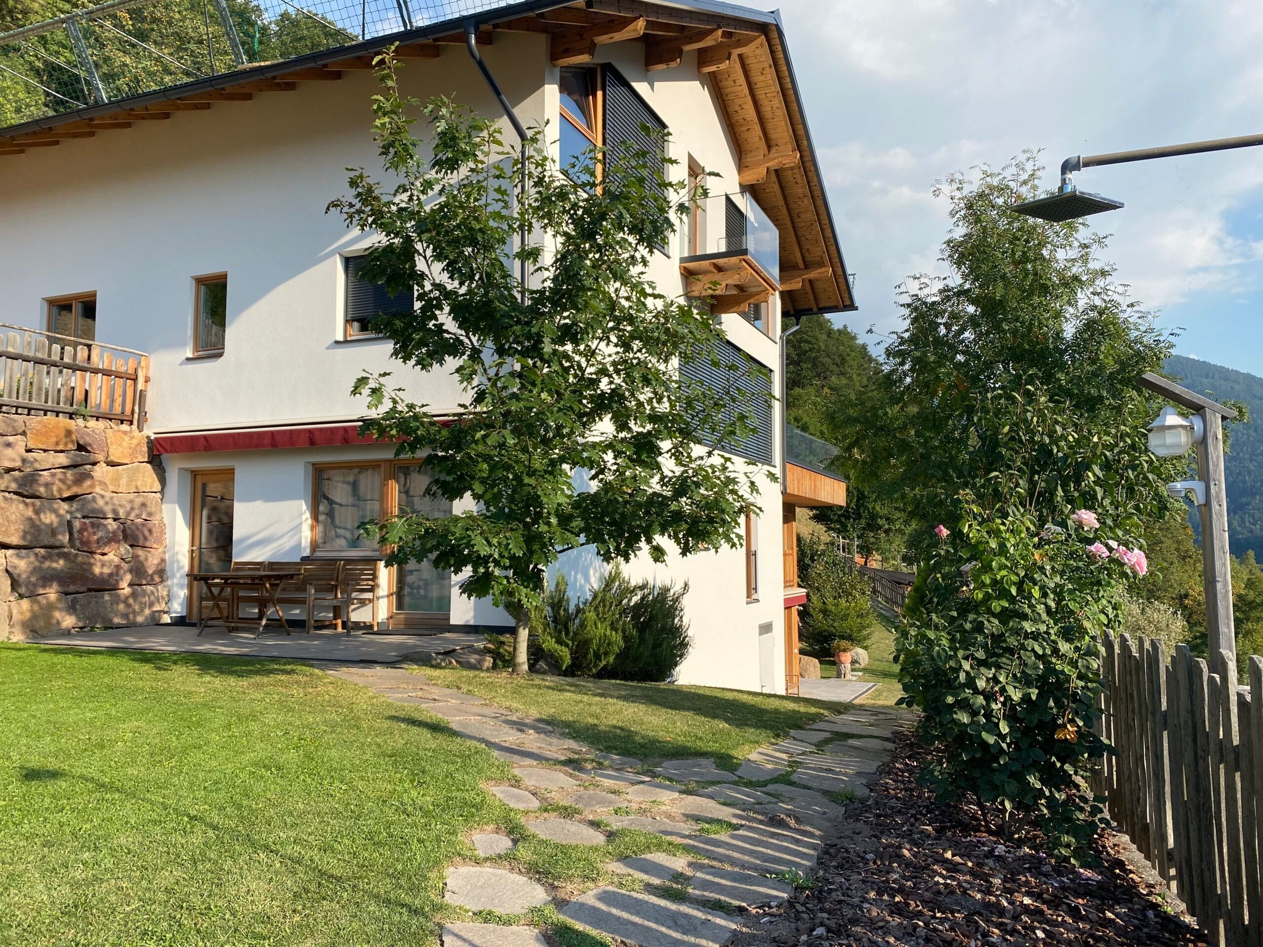 Wohnhaus des Brentwaldhofs mit Holzbalkon, Garten und Steinweg